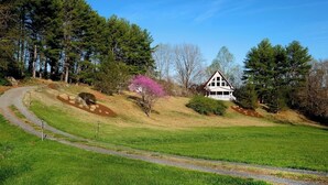 A house with a sloped roof and a large porch, surrounded by a grassy field and trees. - Come and enjoy a beautiful view and relaxing time at Windy Knoll.... (Afton)
