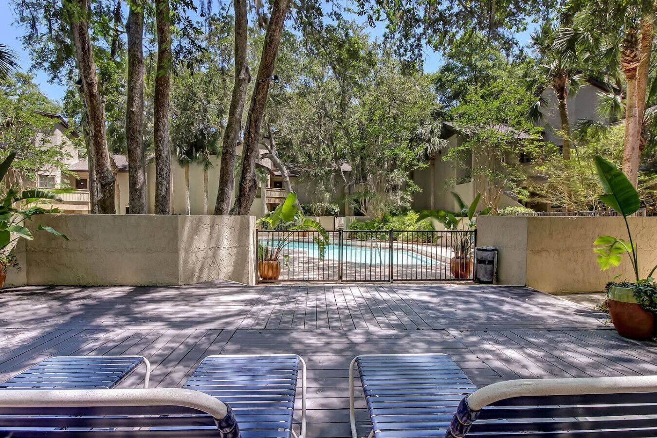 Un espace aménagé au bord de la piscine, avec des chaises longues, une piscine et des arbres environnants.