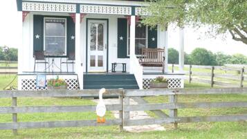 A small building with a porch, a welcome sign, and a wooden fence.