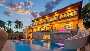 Un hotel moderno con piscina, tobogán y fachada de piedra.