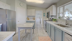 A kitchen with white cabinets, a stainless steel refrigerator, a sink, and a window with a view.