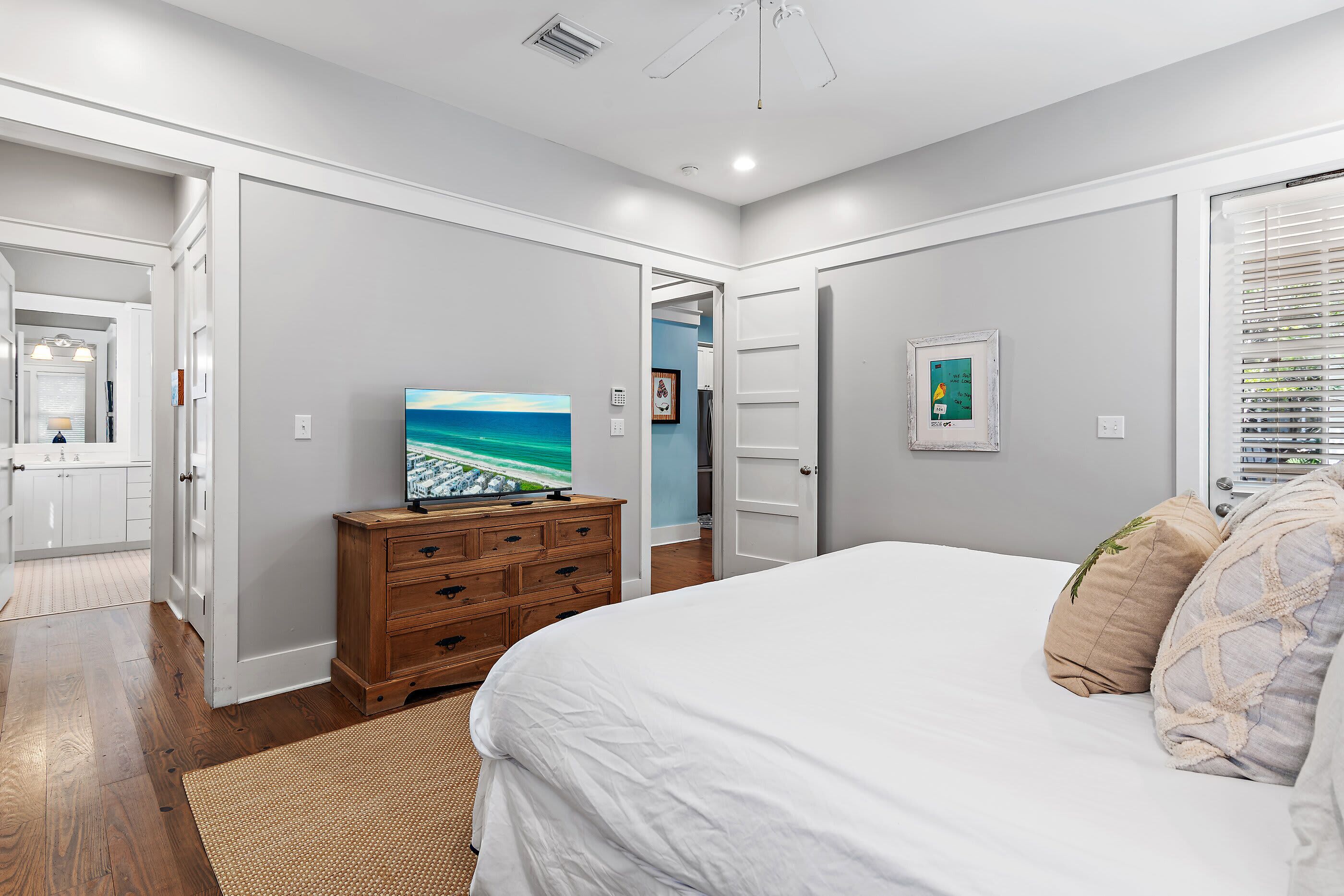 A bedroom with a bed, dresser, and a television displaying a beach scene.