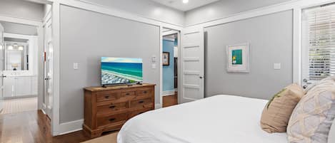 A bedroom with a bed, dresser, and a television displaying a beach scene.