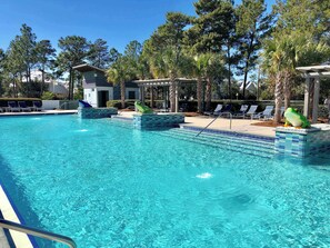 A swimming pool with clear blue water, surrounded by lounge chairs and palm trees. - 35 Lyonia-Watercolor-Community Pool-3 bikes (Santa Rosa Beach)