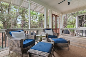 A covered outdoor seating area with wicker furniture and blue cushions.