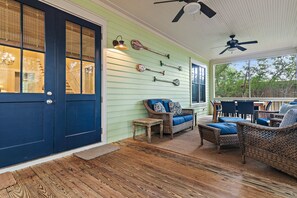 A covered porch with wicker furniture, a ceiling fan, and a wall-mounted paddleboard.