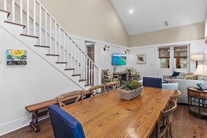 A spacious living area with a wooden dining table, comfortable seating, a staircase, and a television mounted on the wall. - 35 Lyonia-Watercolor-Community Pool-3 bikes (Santa Rosa Beach)