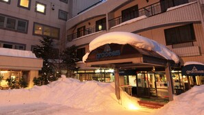 A hotel with a covered entrance, multiple floors, and a snow-covered ground.