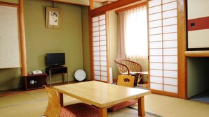 A traditional Japanese room with tatami flooring, a low wooden table, a television, and sliding shoji doors.