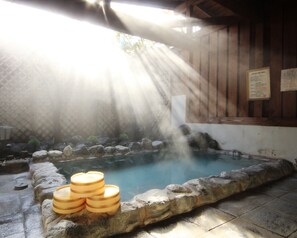 A hot spring area with a stone pool, wooden benches, and a wooden cabin structure. - Hotel Grace Hakuba (Hakuba)