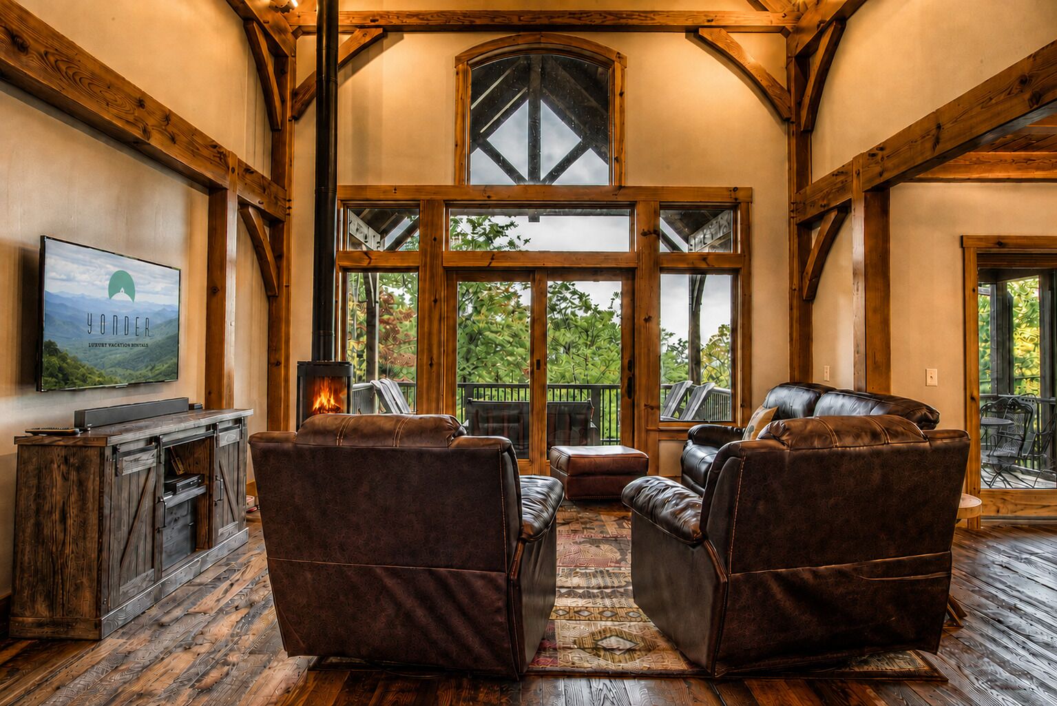 Amplia sala de estar con sofás de cuero, chimenea y ventanas grandes con vistas al exterior.