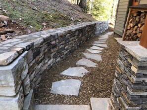 A stone retaining wall with a stepped pathway leading to a building. - Rustic Timber | 5-Bedroom Pet Friendly Black Mountain Retreat with Views (Fairview)