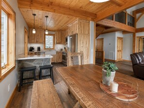 Une cuisine spacieuse avec des meubles en bois, un îlot central en pierre et un coin repas comprenant un banc et une plante en pot.