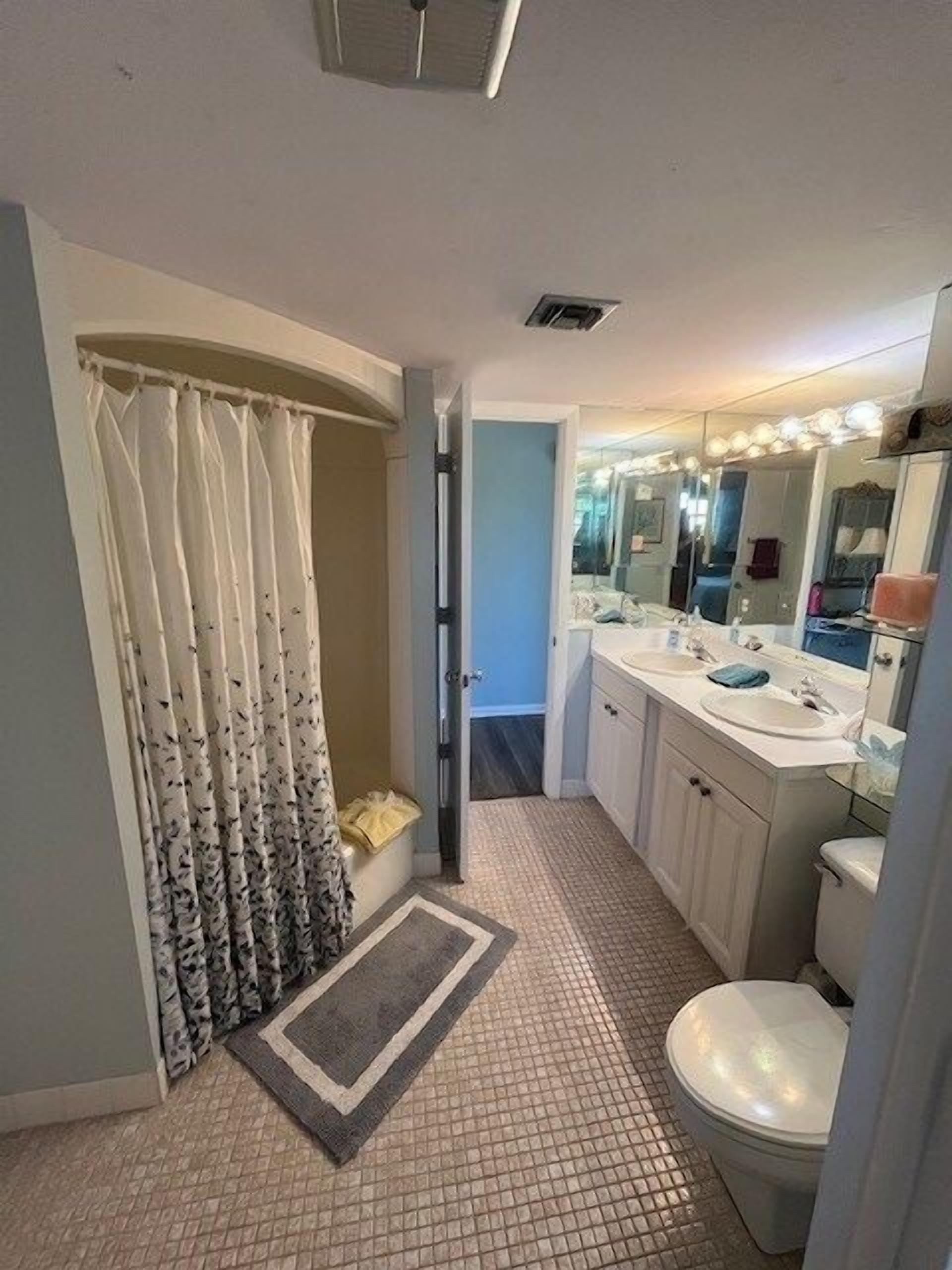 A bathroom with a shower, two sinks, a toilet, and a mirror.