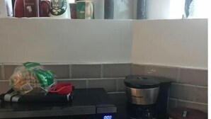 Una cucina con forno a microonde, macchina del caffè e un sacchetto di pane sul bancone.