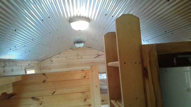 A wooden interior with a sloped ceiling and a visible light fixture. - The Tiny House Experience 6m North of Mnt. View Ark. on N. Riverview  Rd Cr 186  (Mountain View)