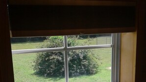 A window with a view of a grassy area and a bush. - The Tiny House Experience 6m North of Mnt. View Ark. on N. Riverview  Rd Cr 186  (Mountain View)