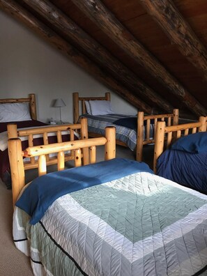 A dormitory room with two wooden bunk beds, each with a headboard and footboard.