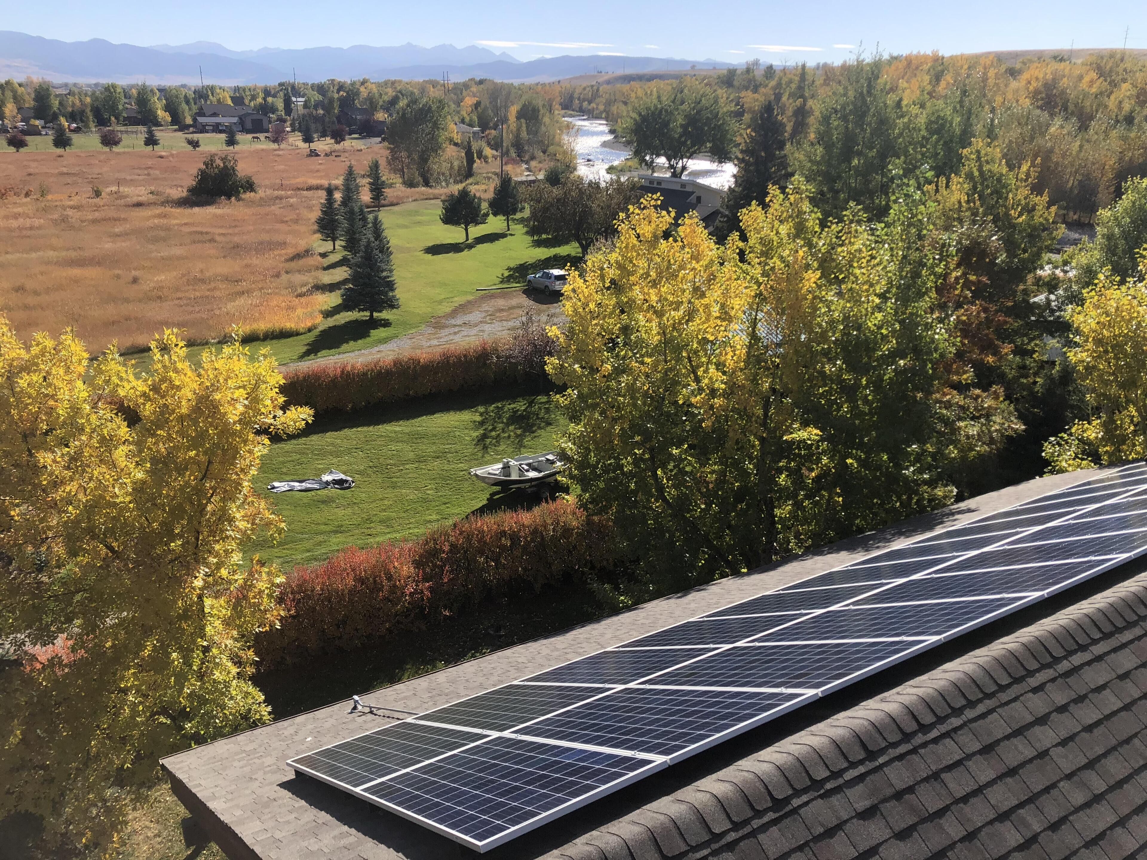 Terraço com painéis solares, um rio e uma área arborizada ao fundo.