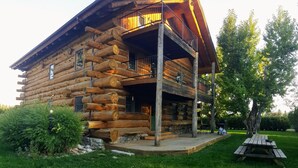 A log cabin with a balcony, a wooden deck, and a picnic table. - Spectacular Large Group Accommodations with Gallatin River access! (Bozeman)