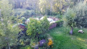 A garden with a wooden deck, a shed, and various plants and flowers. - Spectacular Large Group Accommodations with Gallatin River access! (Bozeman)
