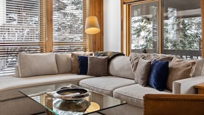 Una sala de estar moderna con una mesa de centro de vidrio, un sofá color beige y una pared de acento de madera.