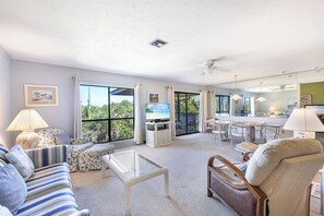 Un vaste espace de vie comprenant un canapé, un fauteuil, une table basse et un coin repas.