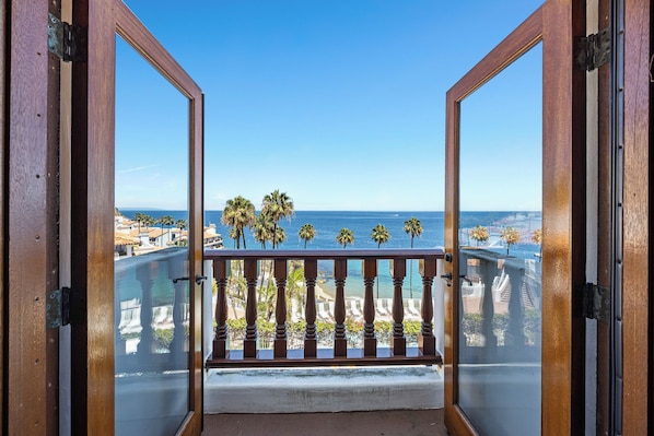 A balcony with a view of the ocean and palm trees.