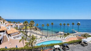 Un resort con piscina, palmeras y vista al océano.