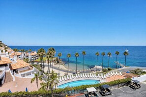 Un complexe hôtelier doté d’une piscine, de palmiers et offrant une vue sur l’océan.