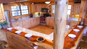 Una cocina con armarios de madera, encimera de granito y una isla central con taburetes.