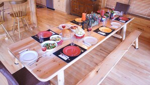 Una mesa de madera dispuesta con platos, cuencos, vasos y cubiertos.