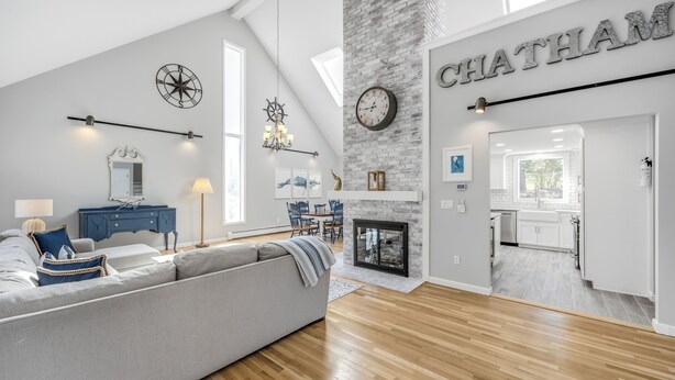 Un salon moderne avec un canapé gris, un plancher en bois, une cheminée et un coin repas.