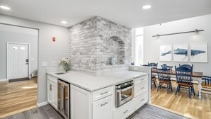 Une cuisine moderne avec des meubles blancs, un mur d’accent en briques et un four encastré.