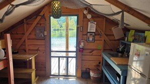 A cabin with a loft bed, a small table, a sink, and a refrigerator. - Castaway lake side canvas cottage scene (Jasonville)