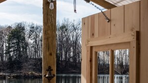 A wooden cabin with a window overlooking a calm lake and forested area. - Castaway lake side canvas cottage scene (Jasonville)
