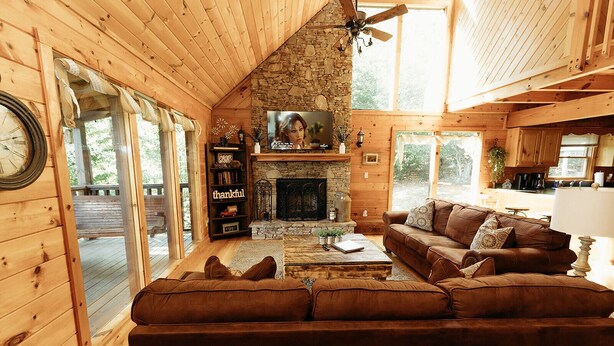 A cozy cabin interior with a stone fireplace, a large window, and a wooden ceiling. - "Rustic Relaxation" Lodge with a Gorgeous View!!! (Sevierville)