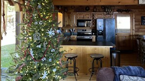 A cozy cabin interior with a decorated Christmas tree, wooden ceiling, and a kitchen area. - "Rustic Relaxation" Lodge with a Gorgeous View!!! (Sevierville)