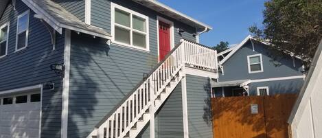 A two-story house with a red door, a white staircase, and a garage.
