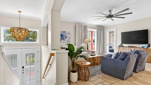 Ein großzügiges Wohnzimmer mit Deckenventilator, einem großen Flachbildfernseher und einer gemütlichen Sitzecke.