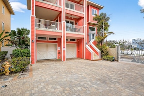 A multi-story building with balconies, a garage, and a paved driveway.