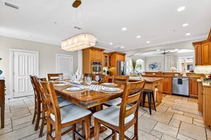 A spacious kitchen with wooden cabinets, a dining table set for six, and a large island with a sink.