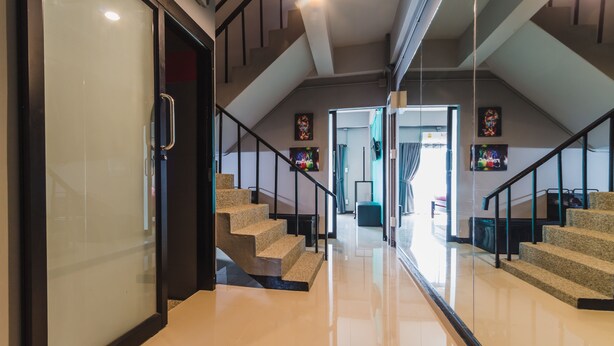 Een modern interieur met een glazen deur, een trap met metalen leuningen, en kunstwerken aan de wanden.