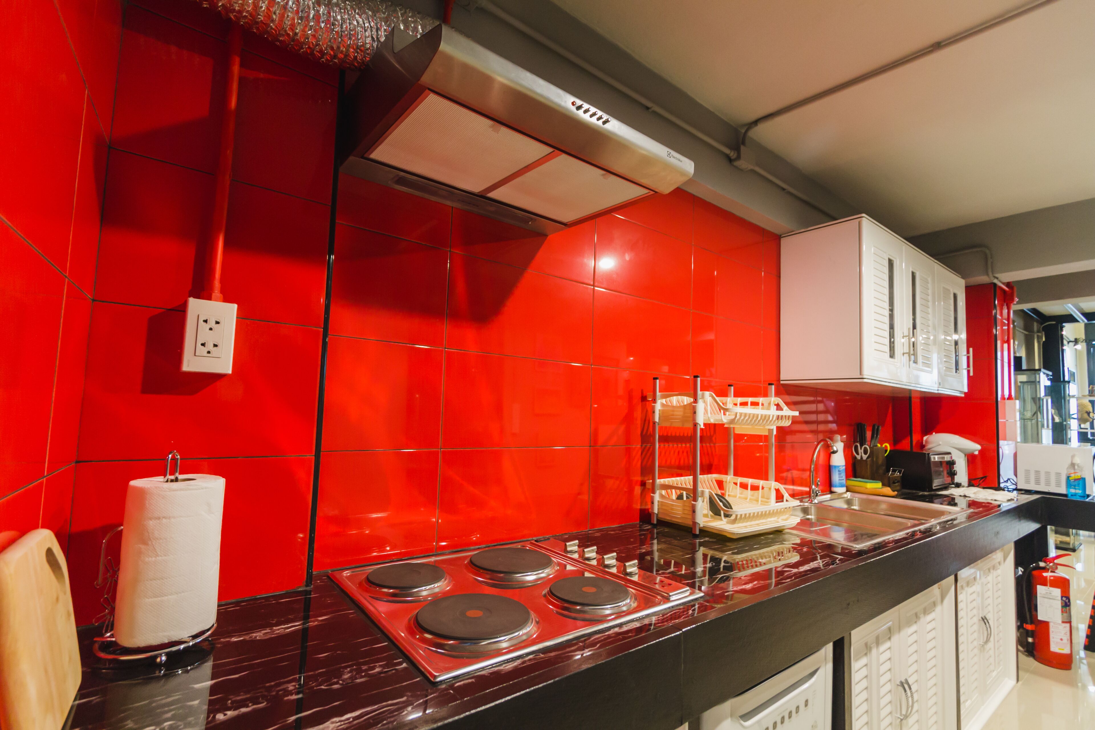 Cozinha com azulejos vermelhos, fogão a gás e armários brancos.