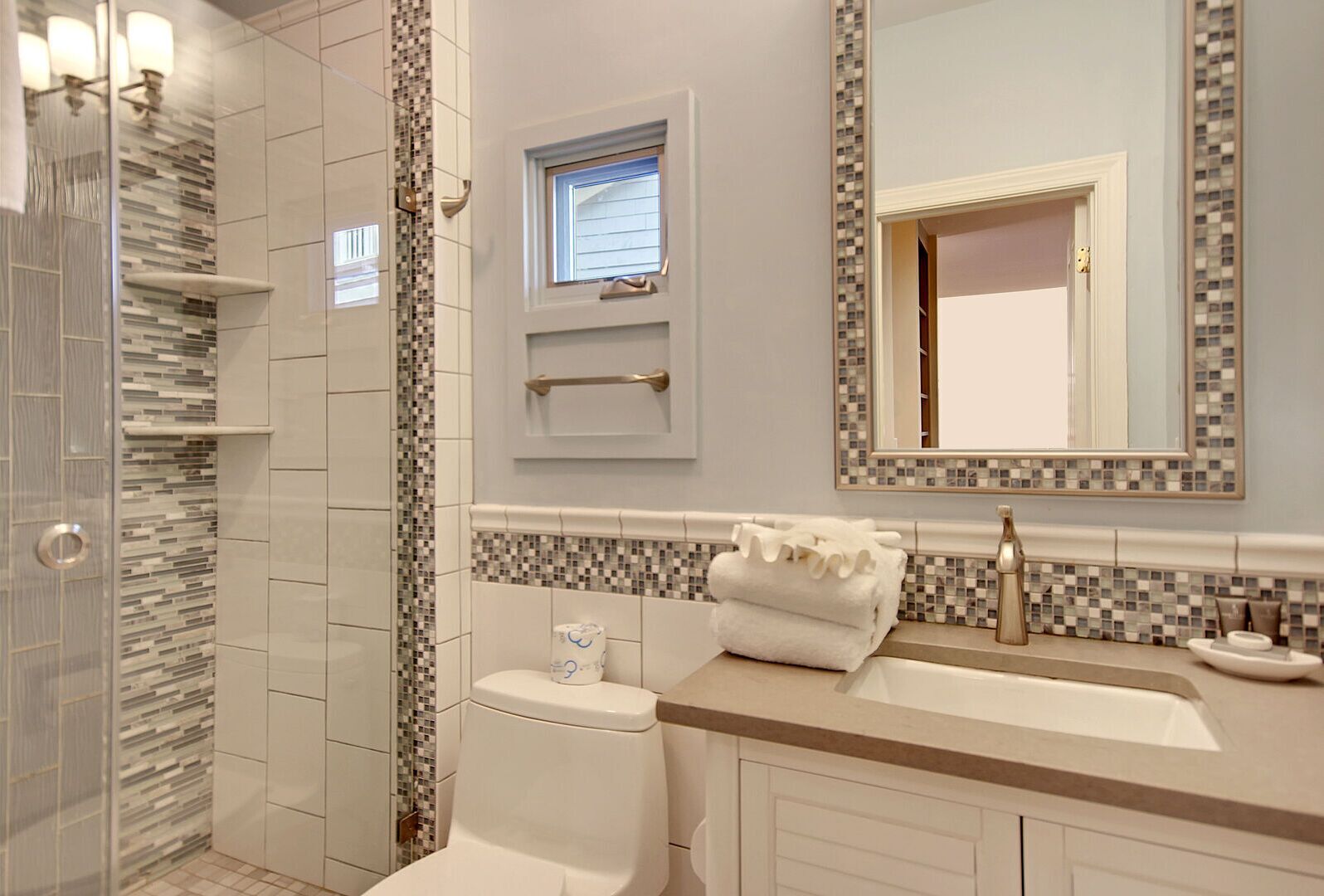 A modern bathroom with a shower, toilet, and sink.