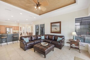 A spacious living room with a large sectional sofa, a dining area, and a kitchen in the background.