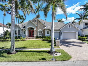 A residential house with a red front door, stone facade, and a garage. - Waterfront Home | Pool, Spa & Direct Boating Access (Marco Island)