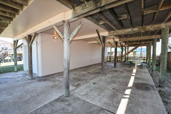 Un patio extérieur partiellement abrité, doté d’un sol en béton et de poutres en bois.