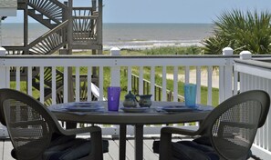 Une terrasse avec une table et des chaises donnant sur la plage.