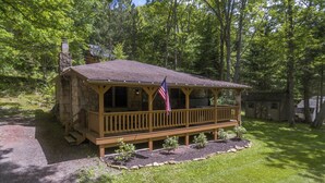 Un chalet rustique doté d’une terrasse en bois, entouré d’une forêt.